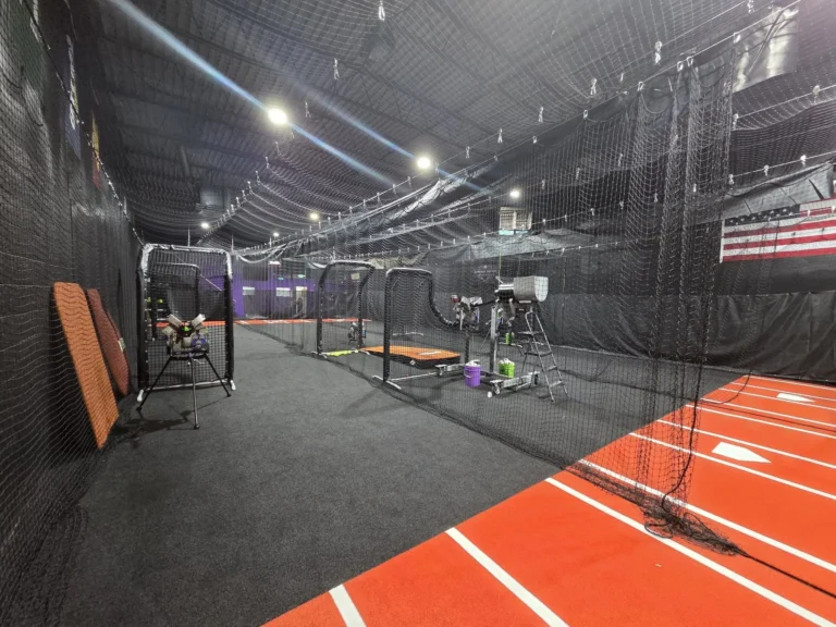 Indoor baseball and softball training facility with batting cages, pitching machines, turf lanes, and netted practice areas